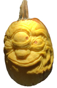A pumpkin carved in intricate detail of a comical three eyed monster face links to pumkin carving event details